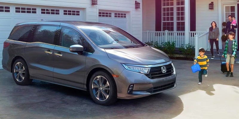 A 2024 Honda Odyssey parked in a driveway with the parents and child outside.