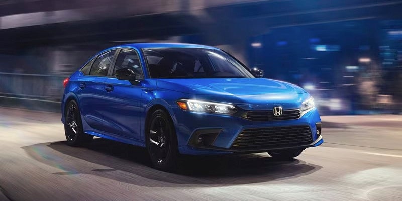 A blue 2024 Honda Civic driving at night.