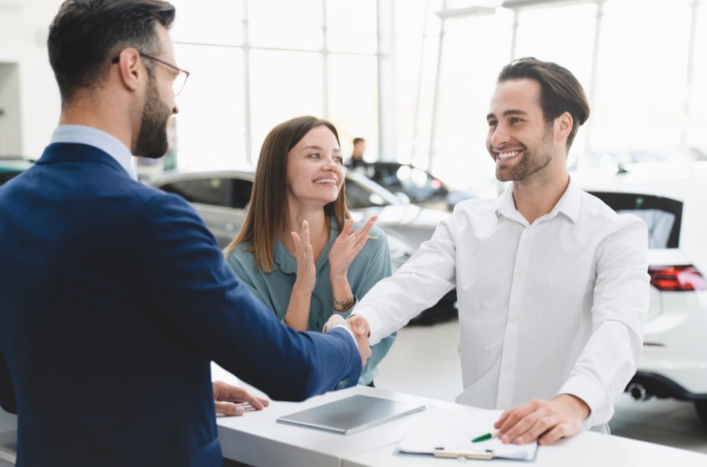 Two customers shaking a finance department member's hand after closing a deal.