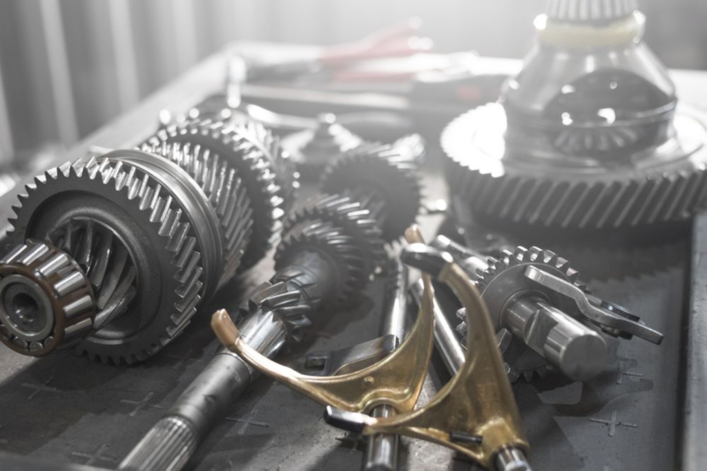 Close-up of mechanical car parts, including gears and tools, on a workbench.
