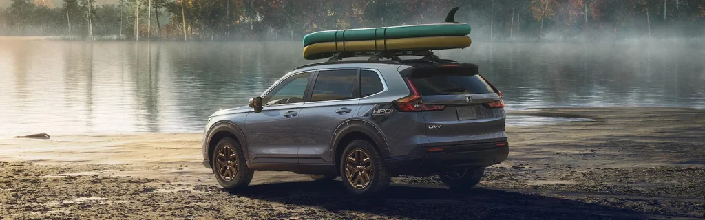 A Honda CR-V parked near a lake with kayaks on the roof.